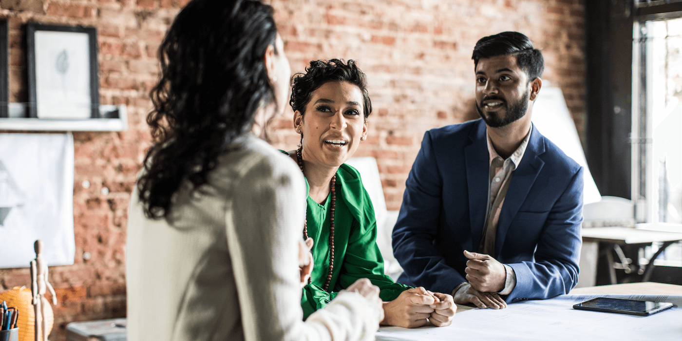 three people talking and smiling in an office