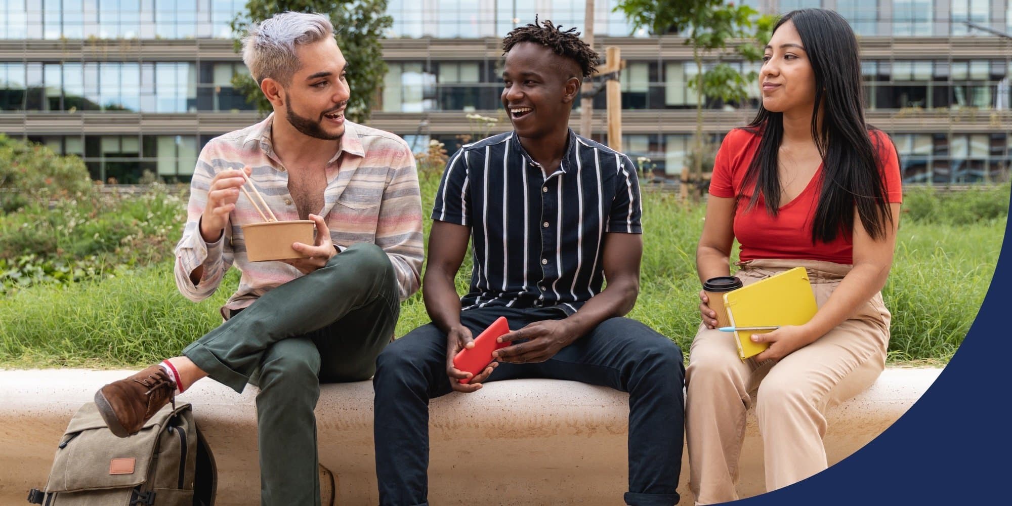 Group of three tech workers sitting on the edge of a concrete planter, talking and eating or holding notebooks