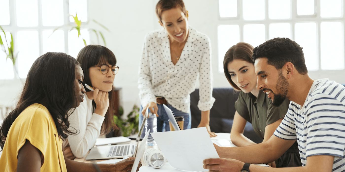 diverse group of colleagues sitting at a table at the office looking at a document