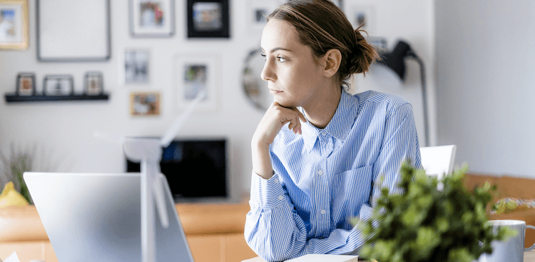 person sitting in front of a laptop, leaning on elbow and staring off into space