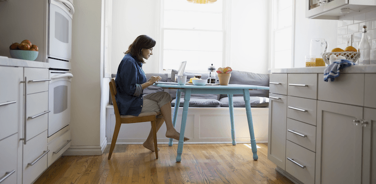 person sitting at a kitchen table working on a laptop