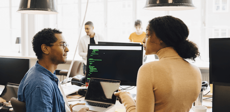 people sitting in an office looking at a computer screen with code on it